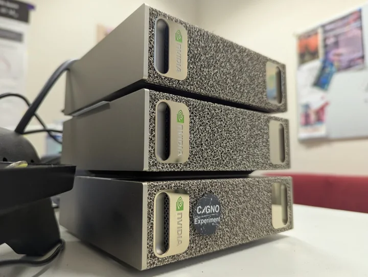 Three NVIDIA DGX Spark computers stacked on a desk, with a CYGNO Experiment sticker on the lower unit