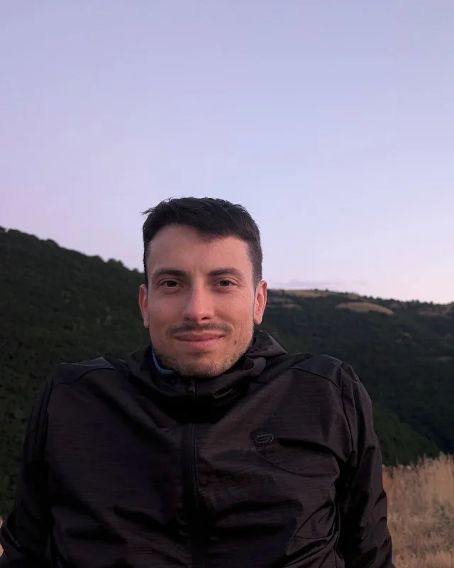 Davide Fiorina outdoors at dusk, with hills behind him