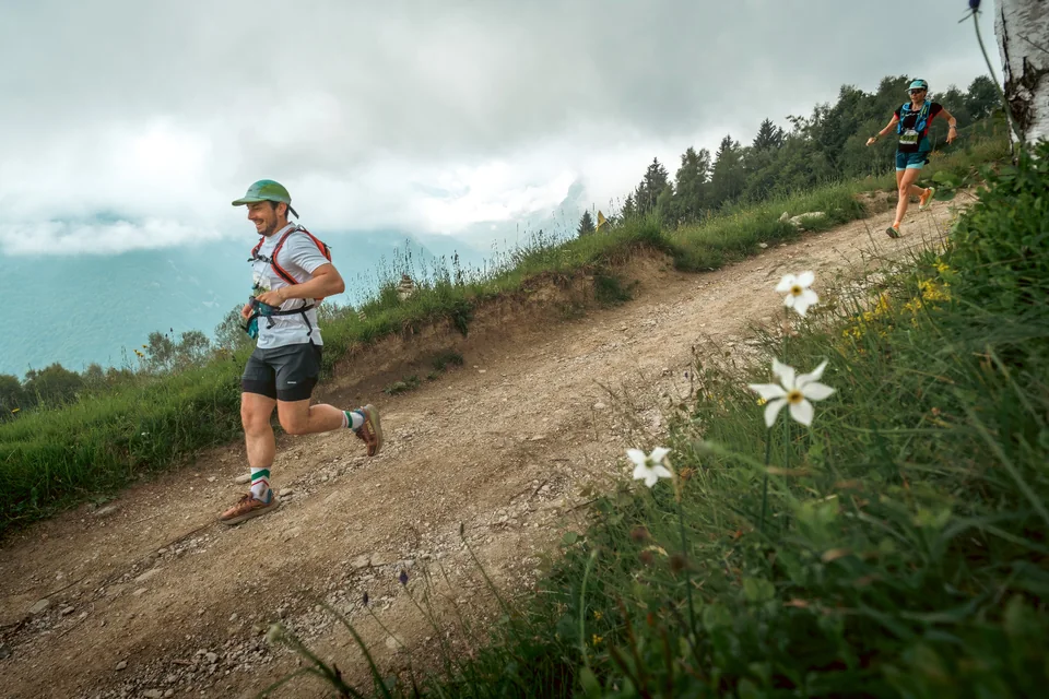 Running along a hillside trail beneath a cloudy sky