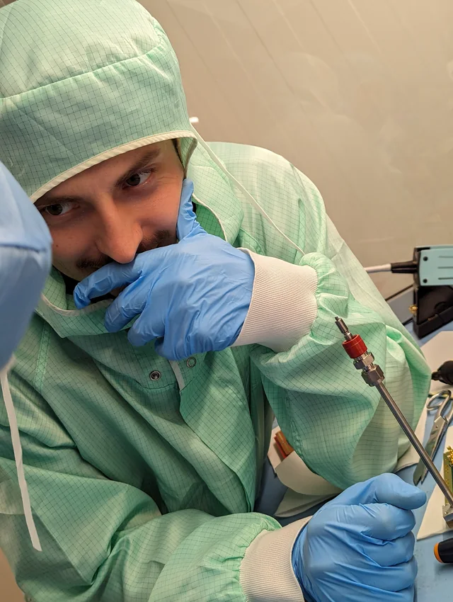 Davide in clean-room clothing, working closely on a detector component
