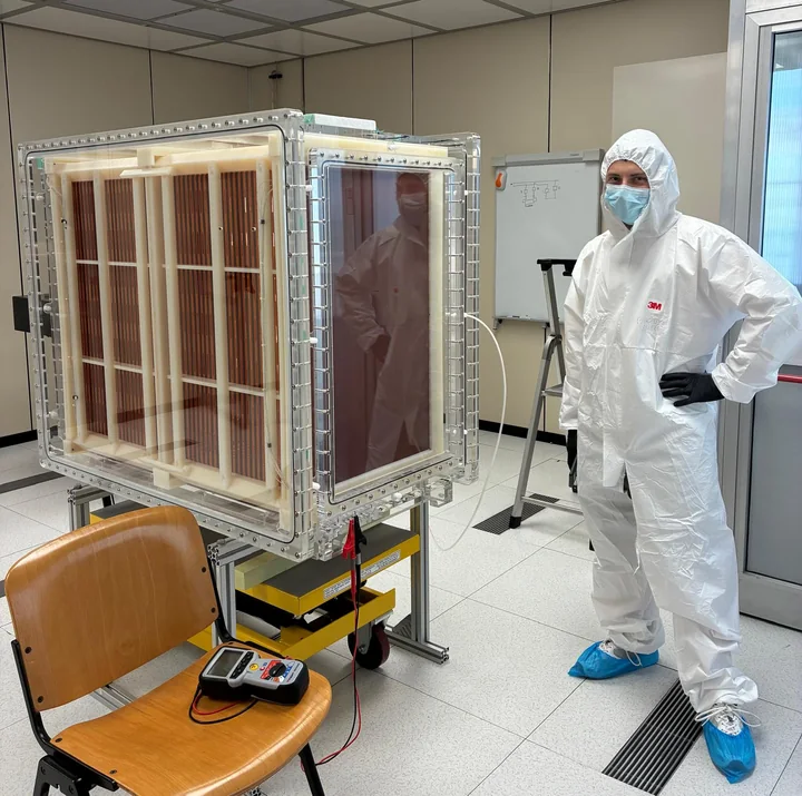 Davide in clean-room clothing standing beside the CYGNO04 time projection chamber